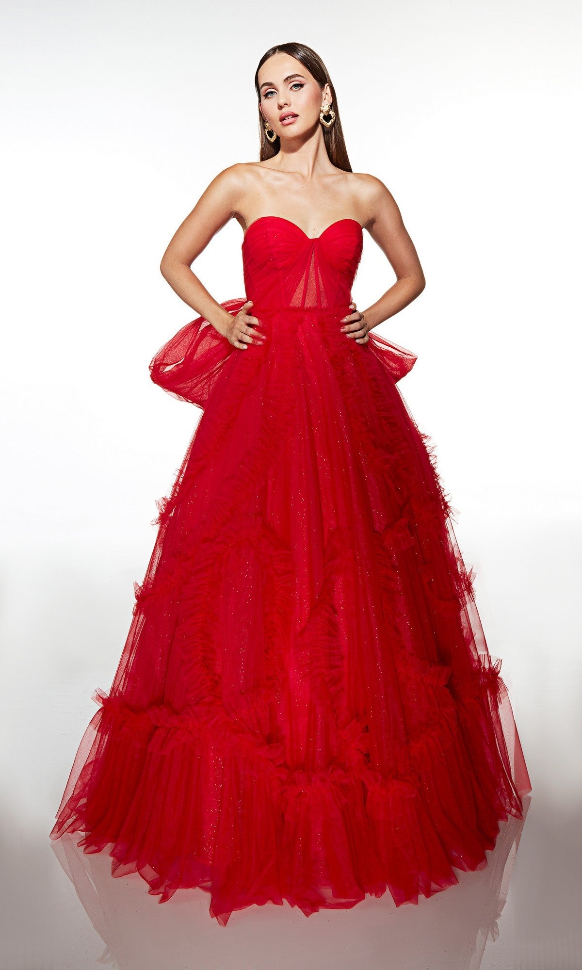 A woman models the Alyce 62119 long prom dress, showcasing its strapless fitted corset bodice and bright red tulle skirt, posed against a plain white background.